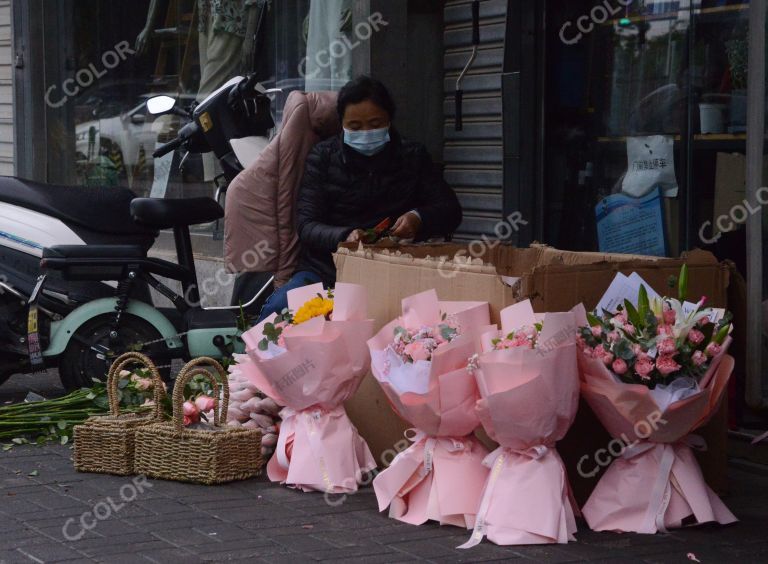疫情防控期的母亲节，鲜花店员工在马路边整理花束