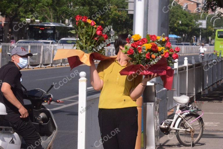 2023年高考首日，十字路口手捧鲜花的女士