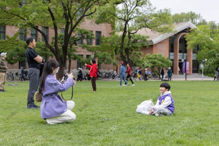 清华大学校园的草坪上给孩子拍照的妈妈